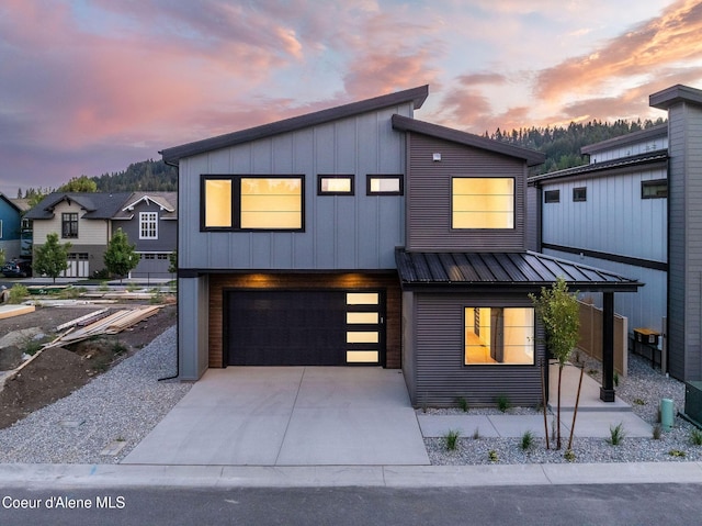 modern home with a garage, board and batten siding, metal roof, and concrete driveway