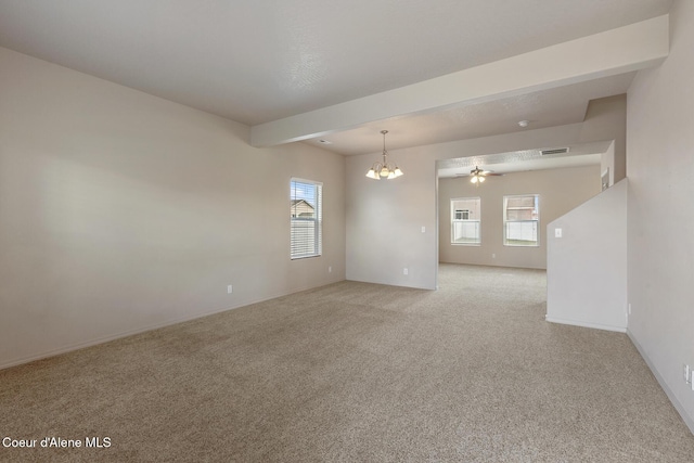 carpeted spare room featuring a healthy amount of sunlight, visible vents, baseboards, and ceiling fan with notable chandelier