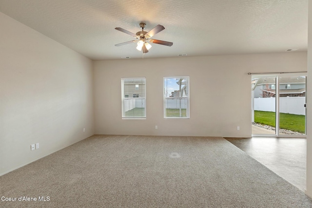 carpeted spare room with ceiling fan, visible vents, and a textured ceiling