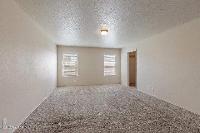 spare room with carpet flooring, a textured ceiling, and baseboards