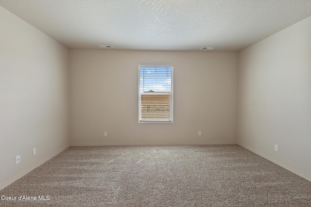 carpeted spare room featuring baseboards, visible vents, and a textured ceiling