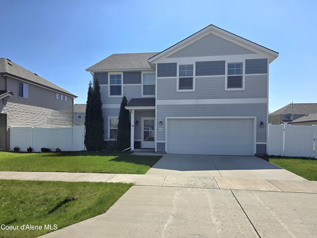 traditional-style home with an attached garage, driveway, fence, and a front yard