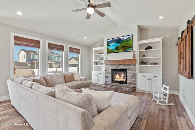 living area with light wood-style floors, lofted ceiling, baseboards, and a barn door