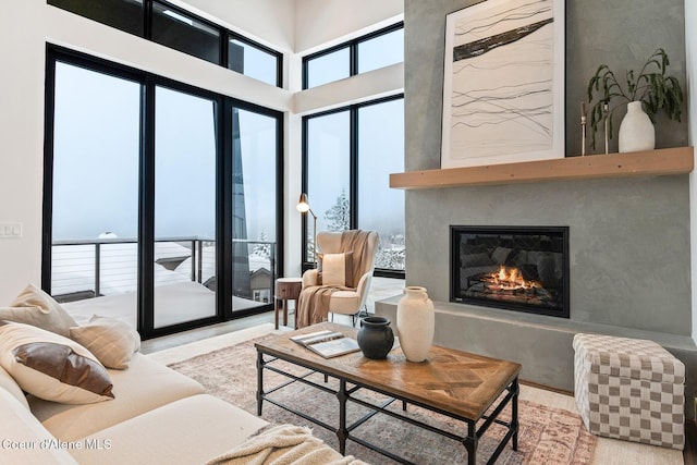 living room with a towering ceiling and a glass covered fireplace