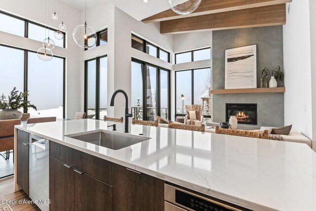 kitchen with plenty of natural light, a glass covered fireplace, open floor plan, a sink, and beam ceiling