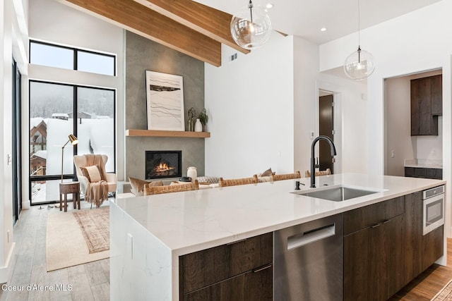 kitchen featuring stainless steel dishwasher, light wood-style flooring, modern cabinets, and a sink