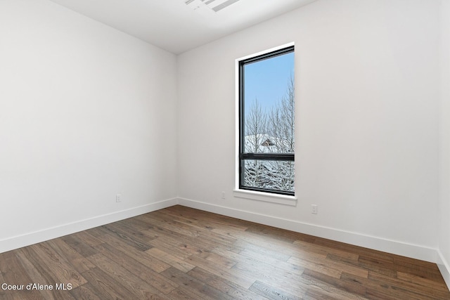 unfurnished room with dark wood-type flooring, visible vents, and baseboards