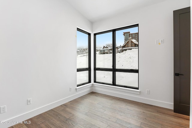 spare room featuring baseboards and wood finished floors