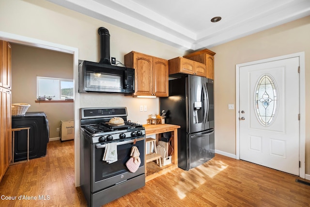 kitchen with baseboards, brown cabinetry, a wood stove, stainless steel appliances, and light wood-style floors