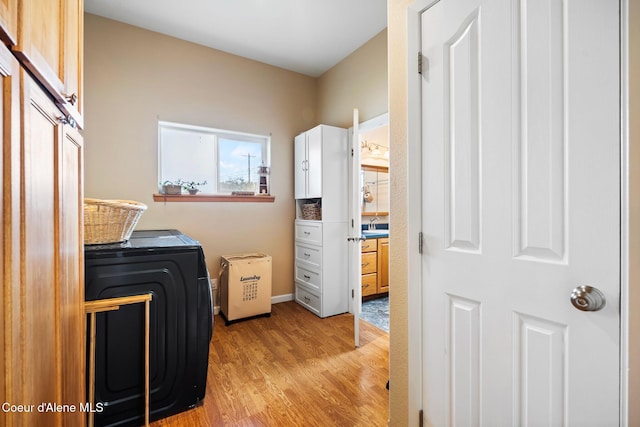 laundry room featuring a sink, cabinet space, and light wood-style floors