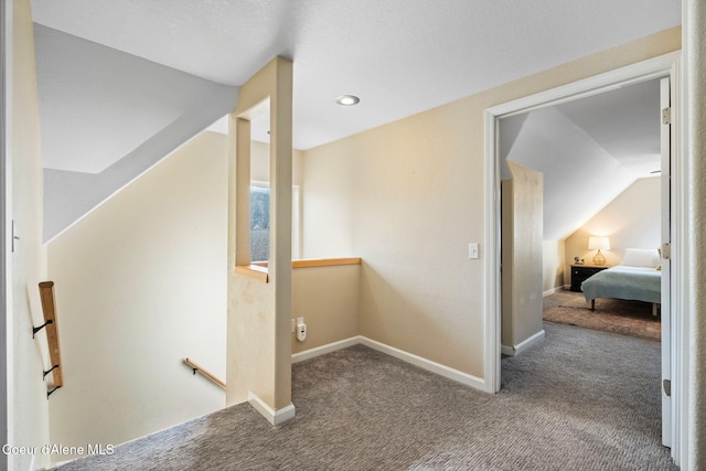 corridor featuring carpet, baseboards, vaulted ceiling, and an upstairs landing