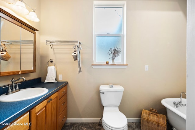 bathroom with baseboards, a freestanding bath, vanity, and toilet