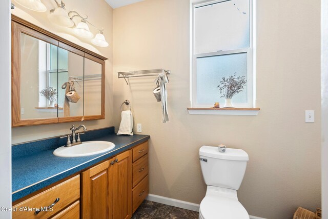 half bathroom with baseboards, vanity, and toilet