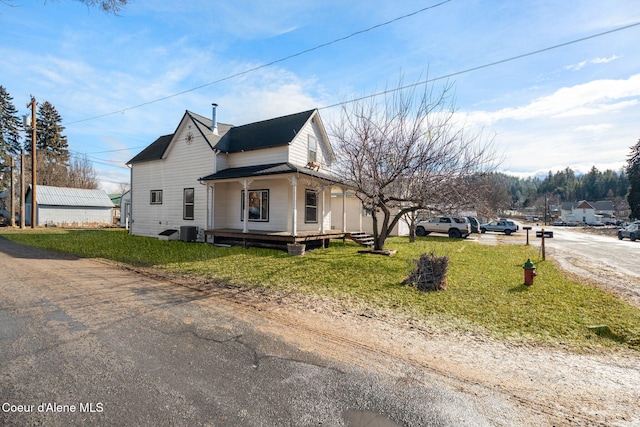 view of side of property featuring cooling unit, covered porch, and a lawn