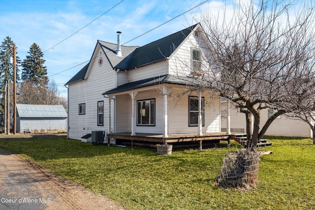 view of front facade with covered porch, a shingled roof, central AC, and a front yard