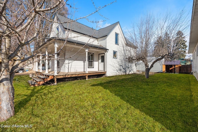 back of property with roof with shingles, fence, and a yard