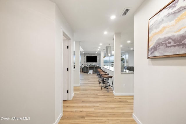 corridor with baseboards, light wood finished floors, visible vents, and recessed lighting