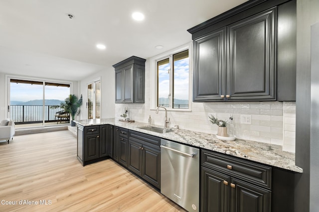 kitchen featuring light stone counters, a sink, decorative backsplash, dishwasher, and light wood finished floors