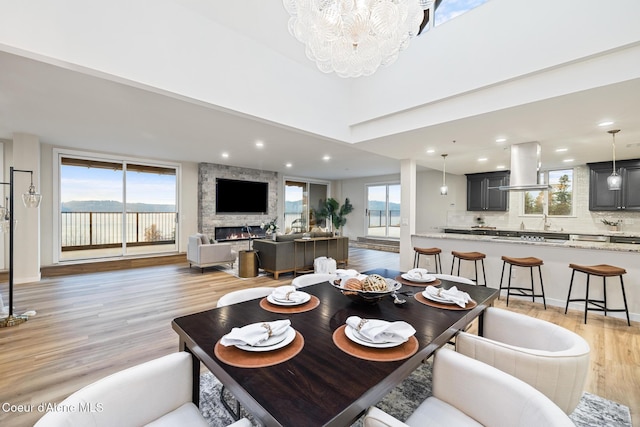 dining room with a wealth of natural light, a fireplace, light wood-style flooring, and recessed lighting