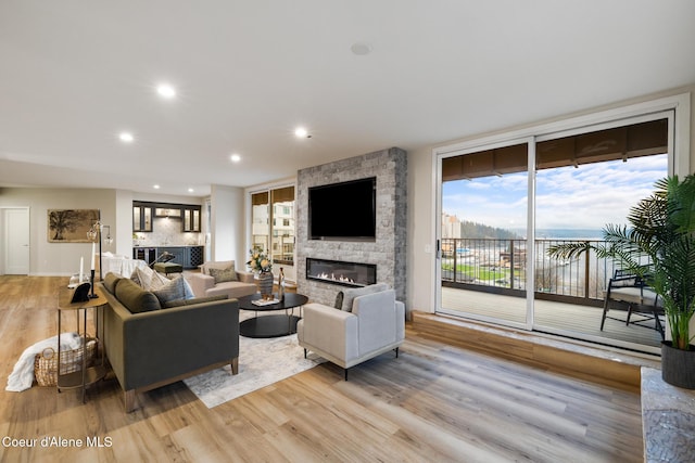 living area with light wood-type flooring, a fireplace, and recessed lighting