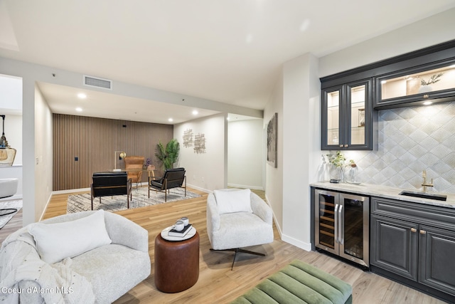 living area with baseboards, visible vents, wine cooler, wet bar, and light wood-type flooring