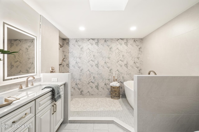 full bath featuring a skylight, tile patterned flooring, a tile shower, vanity, and a freestanding tub