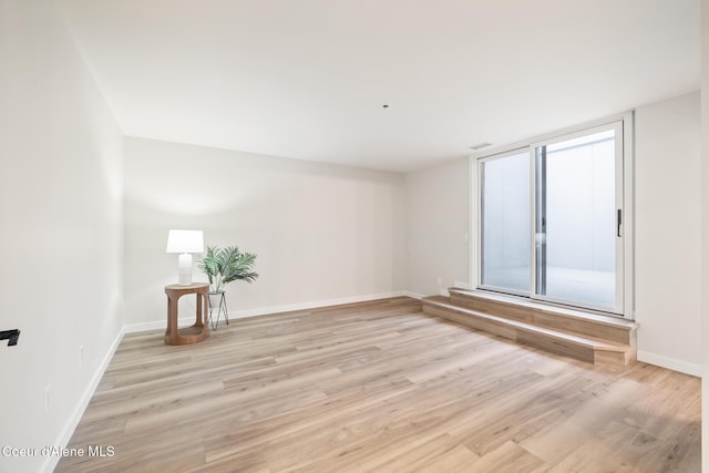 unfurnished room with light wood-style floors, visible vents, and baseboards