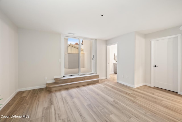 empty room featuring light wood-style flooring, visible vents, and baseboards