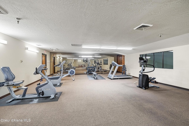 exercise room with visible vents, a textured ceiling, and baseboards