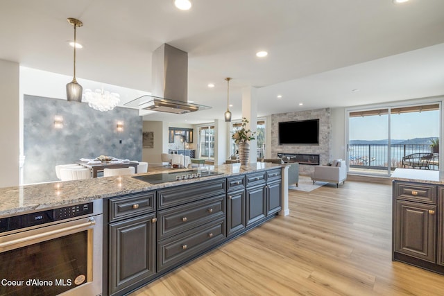 301 N 1st St # 930, Coeur Dalene, ID 83814 - kitchen with black electric stovetop, light wood-style floors, stainless steel oven, open floor plan, and island exhaust hood