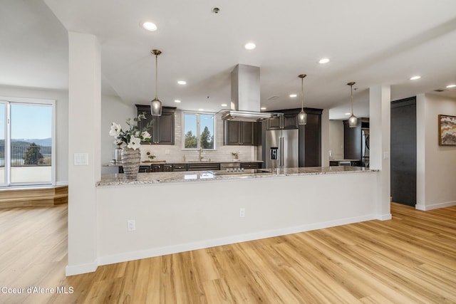 301 N 1st St # 930, Coeur Dalene, ID 83814 - kitchen with a peninsula, high end fridge, island range hood, light wood finished floors, and backsplash