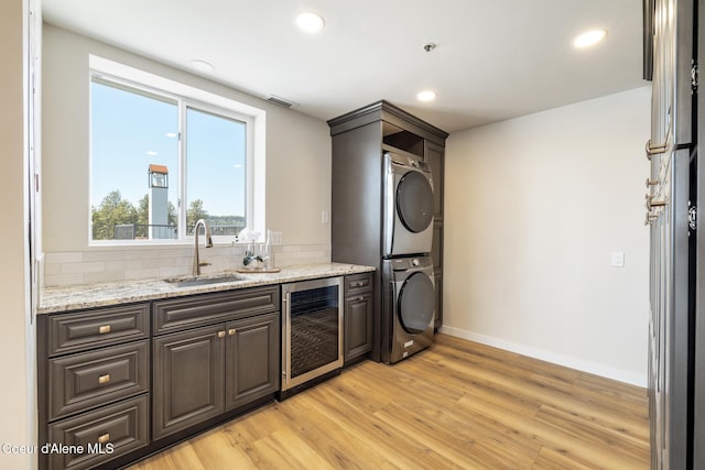 301 N 1st St # 930, Coeur Dalene, ID 83814 - bar with stacked washer / drying machine, a sink, light wood-style floors, beverage cooler, and tasteful backsplash