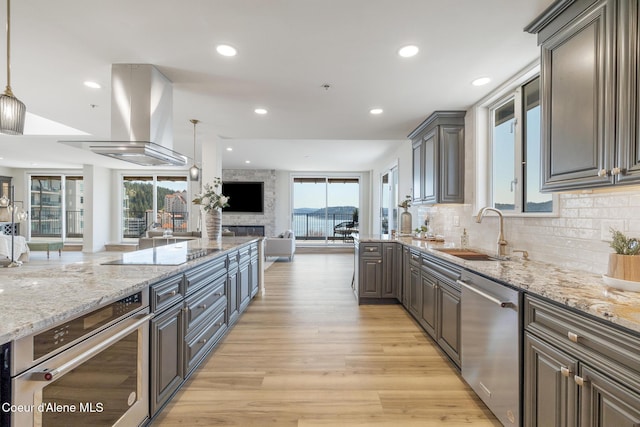 301 N 1st St # 930, Coeur Dalene, ID 83814 - kitchen featuring light stone counters, open floor plan, island exhaust hood, a sink, and stainless steel appliances
