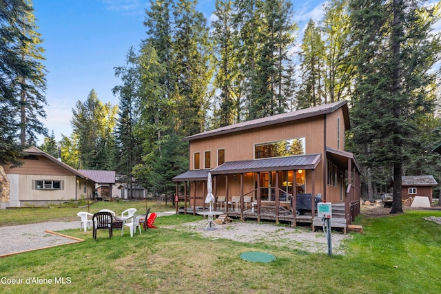 rear view of property with metal roof, a lawn, and an outbuilding