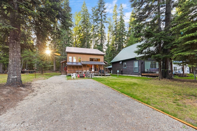 chalet / cabin featuring gravel driveway, metal roof, and a front yard