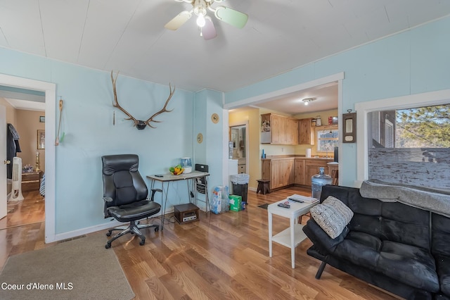 living area with a ceiling fan, visible vents, light wood-style flooring, and baseboards