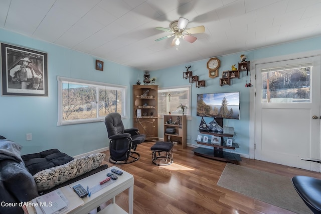 living room with ceiling fan, baseboards, and wood finished floors