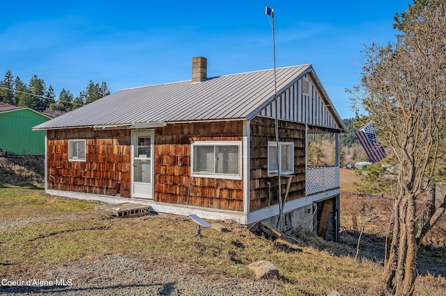 rear view of house with a standing seam roof, metal roof, and a chimney