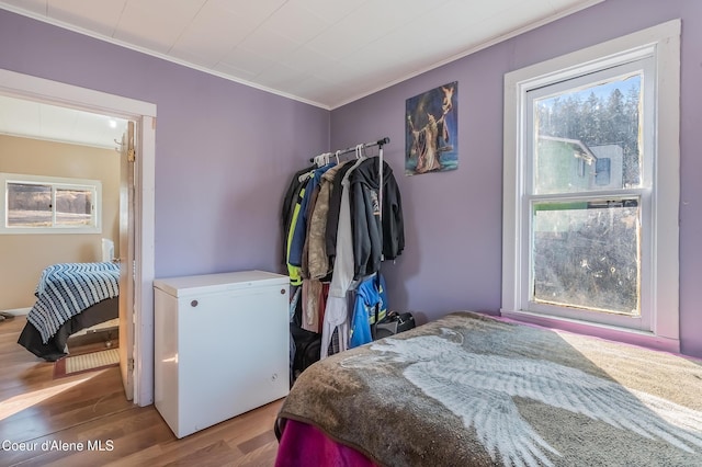 bedroom featuring ornamental molding, fridge, and wood finished floors