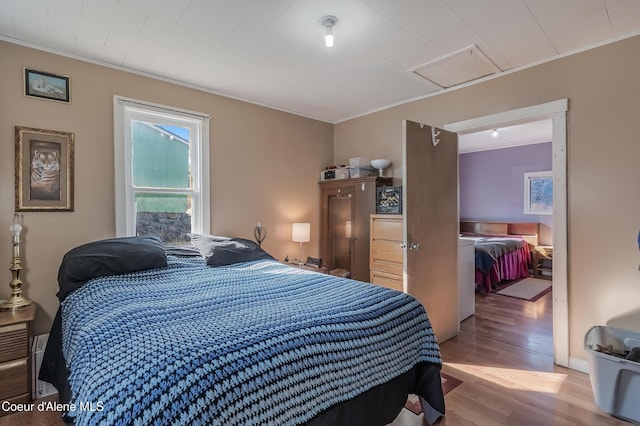 bedroom with ornamental molding and wood finished floors