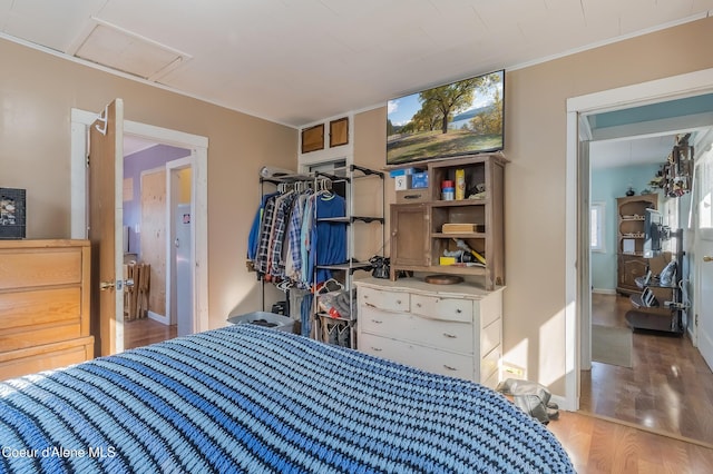 bedroom with ornamental molding and wood finished floors