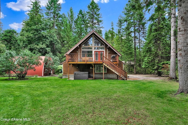 back of house featuring stairway, a wooden deck, a lawn, and a hot tub