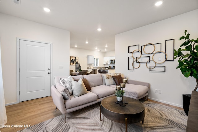 living area featuring baseboards, recessed lighting, and light wood-style floors