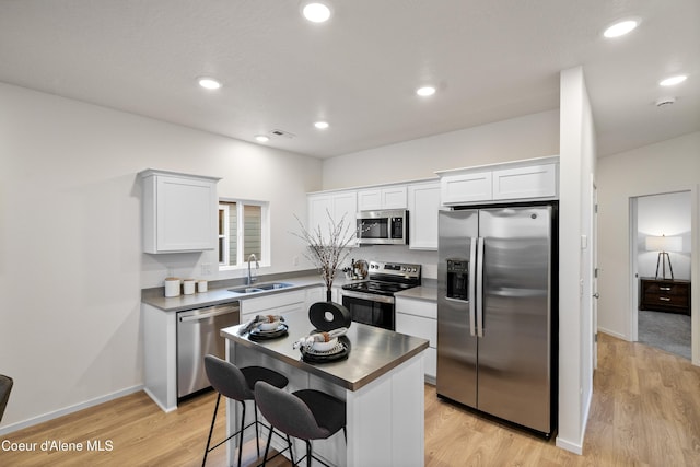 kitchen with recessed lighting, light wood-style flooring, appliances with stainless steel finishes, white cabinetry, and a sink