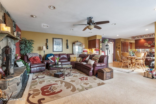 living room with a ceiling fan, recessed lighting, light carpet, and a stone fireplace