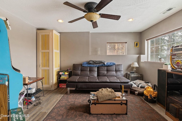 living room with a textured ceiling, visible vents, a wealth of natural light, and wood finished floors