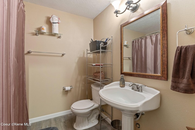 bathroom featuring toilet, a textured ceiling, baseboards, and wood finished floors