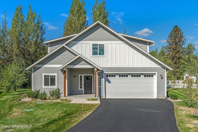 view of front of house featuring board and batten siding, a front lawn, and aphalt driveway