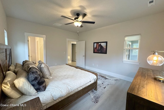 bedroom featuring visible vents, baseboards, a ceiling fan, a textured ceiling, and wood finished floors