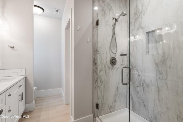 full bathroom featuring vanity, a marble finish shower, baseboards, and visible vents